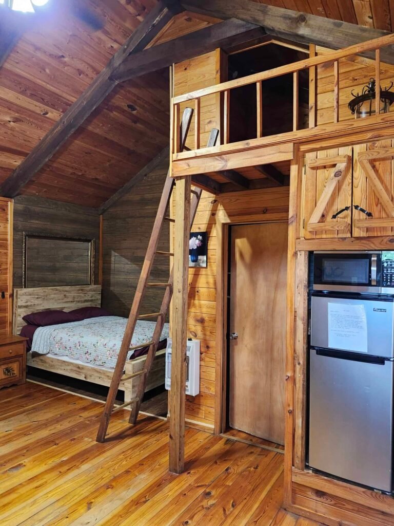 Wood-paneled cabin interior with a bed and loft at Bankhead Resort